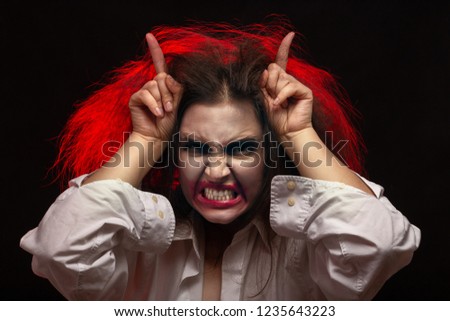 fun crazy young woman with fluffy hair on black background make grimace