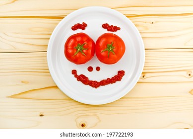 Fun Food For Children - Top View Of Tomatoes And Ketchup Making Smiley Face Served On A White Plate On Wooden Table.