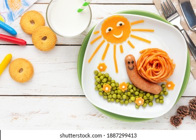 Fun food for kids - Cute little snail made of spaghetti and a sausage, served with green peas and cheddar cheese decoration
