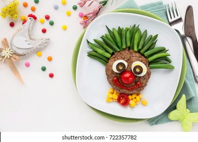 Fun Food For Kids - Cute Smiling Clown Face On A Meat Hamburger Or Ground Meat Pattie With Green Beans For A Healthy Dinner For Children. Creative Cooking Idea