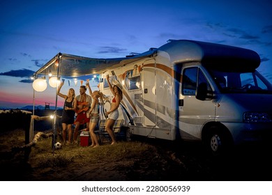 Fun with friends in camp, in front of rv. Young group of people dancing, playing guitar, and celebrating. Summertime togetherness. Travel, weekend, lifestyle concept. - Shutterstock ID 2280056939