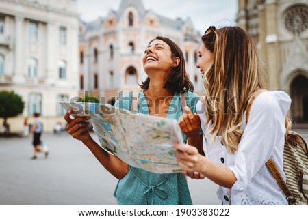 Fun, friends, travel and tourism concept. Beautiful girls looking for direction in the city