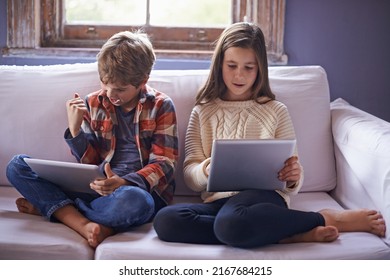 Fun and games on the couch. Shot of a young brother and sister playing on their digital tablets. - Powered by Shutterstock