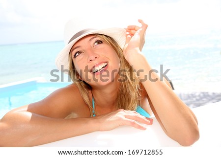 Fun girl with hat suntanning by the pool