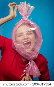 Fun Girl With Head Inside Candy Wrapper On Blue Background