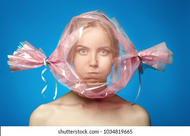 Fun Girl With Head Inside Candy Wrapper On Blue Background