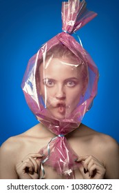 Fun Girl With Head Inside Candy Wrapper On Blue Background