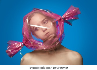 Fun Girl With Head Inside Candy Wrapper On Blue Background