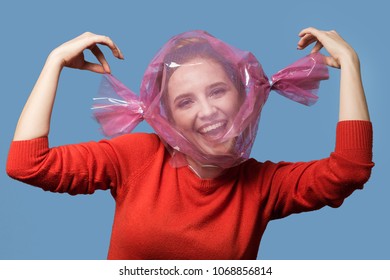 Fun Girl With Head Inside Candy Wrapper On Blue Background