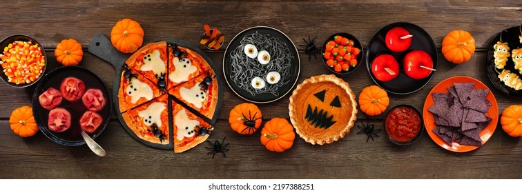 Fun Halloween dinner party table scene over a dark wood banner background. Above view. Pizza, jack o lantern pumpkin pie, candy apples, eyeball spaghetti, snacks and spooky punch. - Shutterstock ID 2197388251