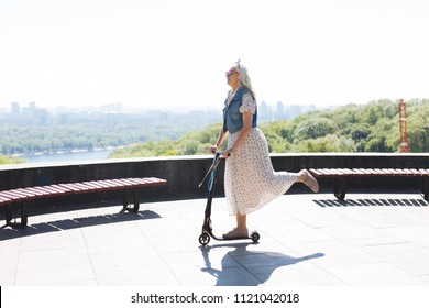 So Fun. Happy Elderly Woman Riding A Scooter While Enjoying Her Walk