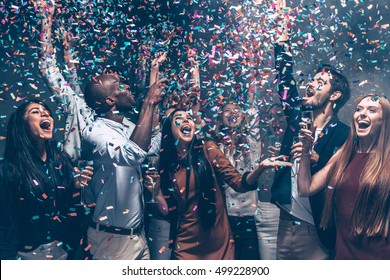 Fun Hunters. Group Of Beautiful Young People Throwing Colorful Confetti And Looking Happy