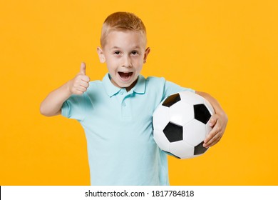 Fun Inspired Little Kid Boy 5-6 Years Old Football Fan In Blue T-shirt Cheer Up Support Favorite Team, Hold In Hands Soccer Ball Isolated On Yellow Background. Sport Family Leisure Lifestyle Concept