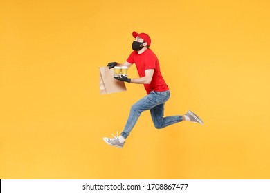 Fun Jumping Delivery Man Guy Employee In Red Cap Mask Gloves Hold Craft Paper Packet Food Coffee Isolated On Yellow Background Studio. Service Quarantine Pandemic Coronavirus Virus 2019-ncov Concept