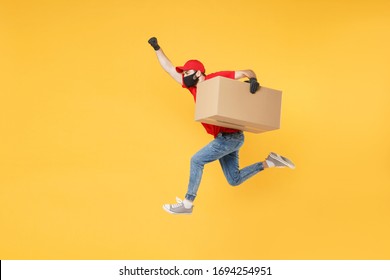 Fun jumping delivery man in red cap t-shirt uniform sterile face mask gloves isolated on yellow background studio Guy employee courier Service quarantine pandemic coronavirus virus 2019-ncov concept