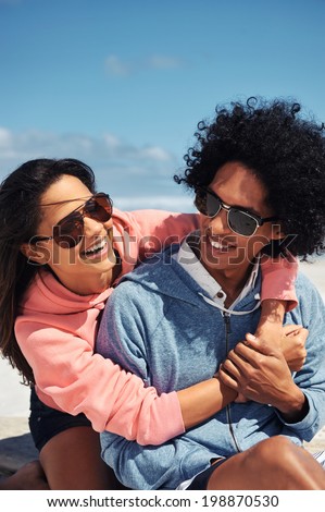Fun Latino couple at the beach embracing and in love smiling