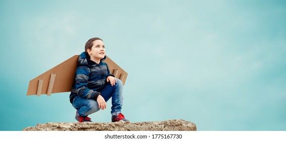 Fun Little boy dreams of becoming an aviator while playing a paper plane at the blue sky background outdoors. Concept of business development and innovation prospects