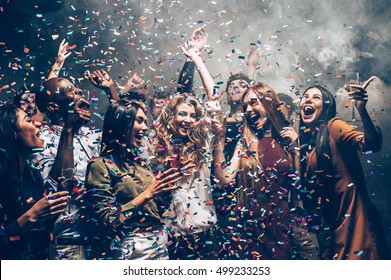 Fun in motion. Group of beautiful young people throwing colorful confetti while dancing and looking happy