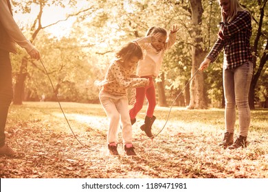 Fun At Park. Cheerful Family Playing With Jump Rope Together In Park.