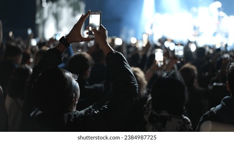 Lot fun people record music video use mobile phone. Fan crowd shoot k pop live concert. Many men hang out cool rave fest. Joy group chill night club hall. Dj star raise hand up. Make light glow photo. - Powered by Shutterstock