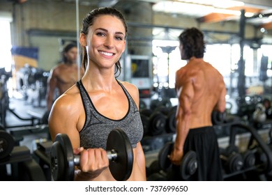 Fun Playful Energetic Female Health And Nutrition Fitness Expert Exercising With Weights At Gym