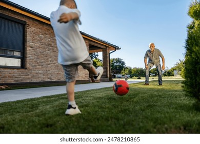 Fun playful grandson and his grandfather playing football in backyard together. - Powered by Shutterstock