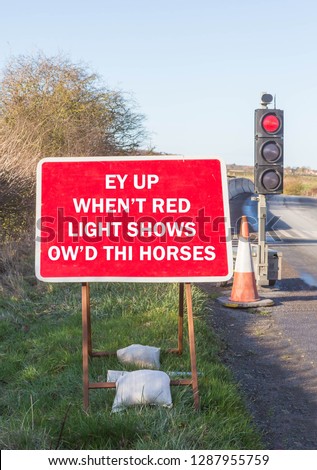 Fun road sign instructing drivers to stop when the red light shows written in a Yorkshire dialect.
