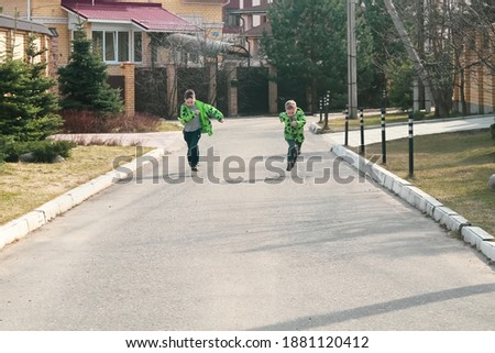 A fun running competition between two children of European boys in a green jacket. Who will come running first. Two children race in the spring.