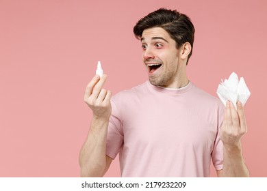 Fun shocked sick unhealthy ill allergic man has red eyes runny stuffy sore nose suffer from allergy symptoms hay fever hold paper napkin use nasal drops isolated on pastel pink color background studio - Shutterstock ID 2179232209