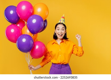 Fun surprised shocked young woman wears casual clothes hat celebrating hold bunch of colorful air balloons do winner gesture isolated on plain yellow background. Birthday 8 14 holiday party concept - Powered by Shutterstock