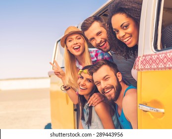 Fun time with friends. Group of happy young people smiling at camera while sitting inside of retro mini van - Powered by Shutterstock