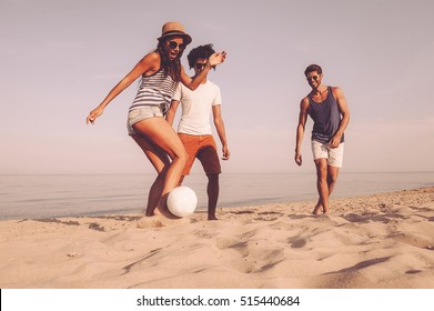 Fun time with friends. Three cheerful young people playing with soccer ball on the beach  - Powered by Shutterstock