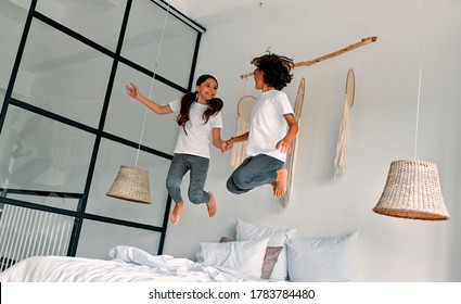 It's fun time! Sister and brother are holding hands and jumping on bed. Children at home - Shutterstock ID 1783784480