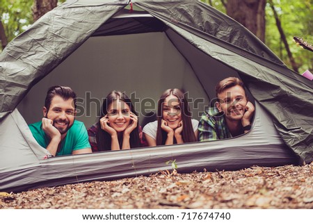 So fun together! Two lovely couples lying down in the tent in a campground, so happy, smiling, relaxing and enjoying