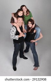 Fun and Unusual Family Portrait of Husband Wife and 3 Daughters on Grey Background