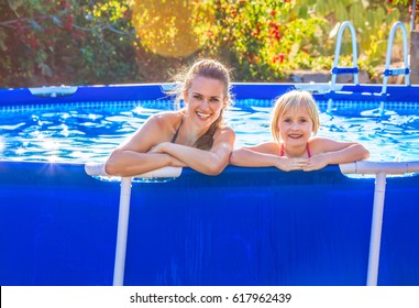 Fun weekend alfresco. Portrait of happy active mother and child in swimsuit in the swimming pool relaxing - Powered by Shutterstock