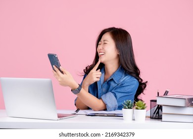 Fun Young Asian Business Woman Sit Work At White Office Desk. She Doing Selfie Shot On Mobile Phone No Isolated On Pink Background.