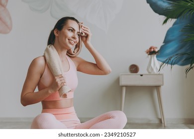 Fun young happy sweating strong sporty athletic fitness trainer instructor woman 20s in pink tracksuit doing yoga exercises close eyes using towel sit on mat floor at home gym indoor Workout concept - Powered by Shutterstock