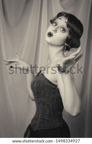 fun young woman with vintage pinup makeup making dolly face looking at camera, monochrome