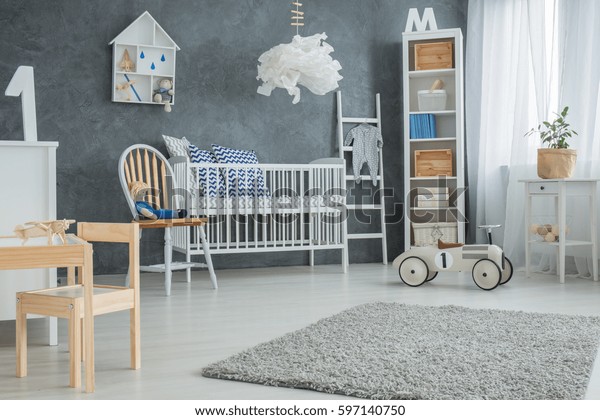Functional baby bedroom with grey wall and\
white furniture