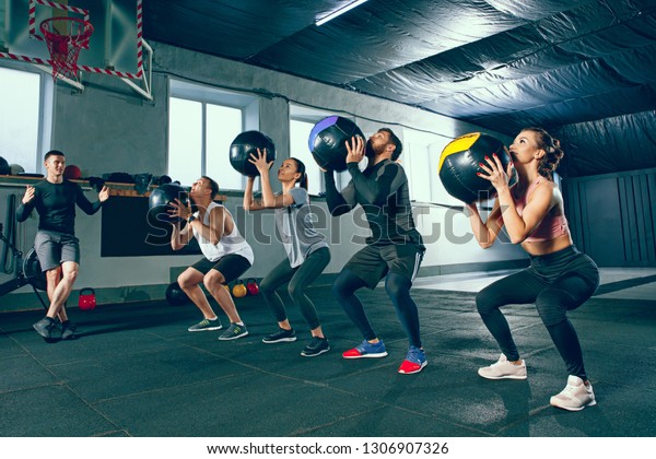 Functional fitness\
workout at the gym with medicine ball. The group of young people\
during training session. Fit athletic men and women at health club.\
Healthy lifestyle\
concept