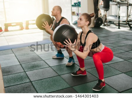 Сouple functional training. Sporty man and fit woman do exercise with medicine ball in gym