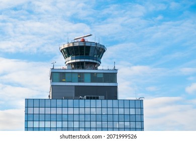 Functioning airport control tower with transparent booth. Air transport command post on multi-storey building top, blue sky light clouds background.Aircraft control and airfield observation concept.