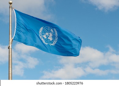 Fundy National Park, NB, Canada - June 30, 2020: United Nations flag flying in the wind on a flagpole against a partially cloudy sky.