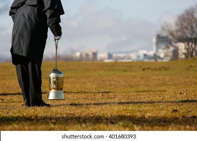 Funeral Director, Undertaker, Starting To Scatter Ashes Of A Cremated Human On A Designated Field For Ash Scattering. Death, Cremation, Funeral, Day Of The Dead Concept. 
