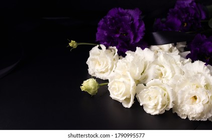 Funeral Flowers Of White And Purple Eustoma On A Black Background. Copy Space