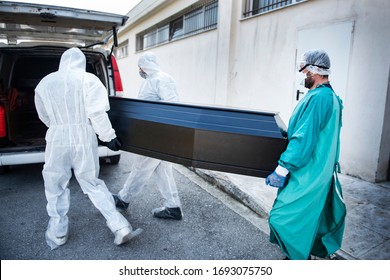 Funeral Home Employees Wear Protective Suits To Protect Themselves From Coronavirus, As They Carry A Coffin.