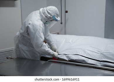 Funeral hospital employee Personal wear Protective Equipment(PPE) to protect himmselves from Coronavirus,as he move a dead body inside bag to the morgue. - Shutterstock ID 1699616911