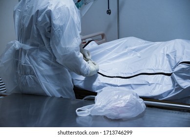 Funeral Hospital Employee Personal Wear Protective Equipment(PPE) To Protect Himmselves From Coronavirus,as He Move A Dead Body Inside Bag To The Morgue.