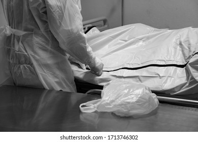 Funeral Hospital Employee Personal Wear Protective Equipment(PPE) To Protect Himmselves From Coronavirus,as He Move A Dead Body Inside Bag To The Morgue.